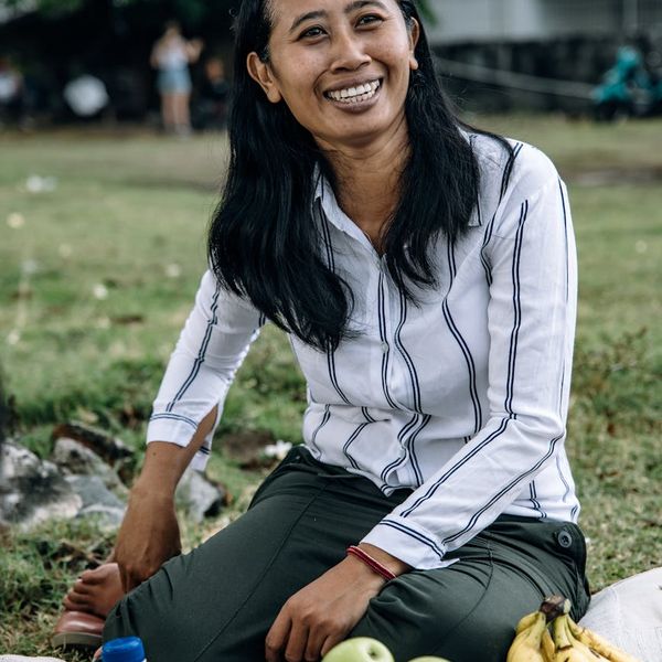 Woman smiling with eyes closed, enjoying the sun and fresh air in a field.